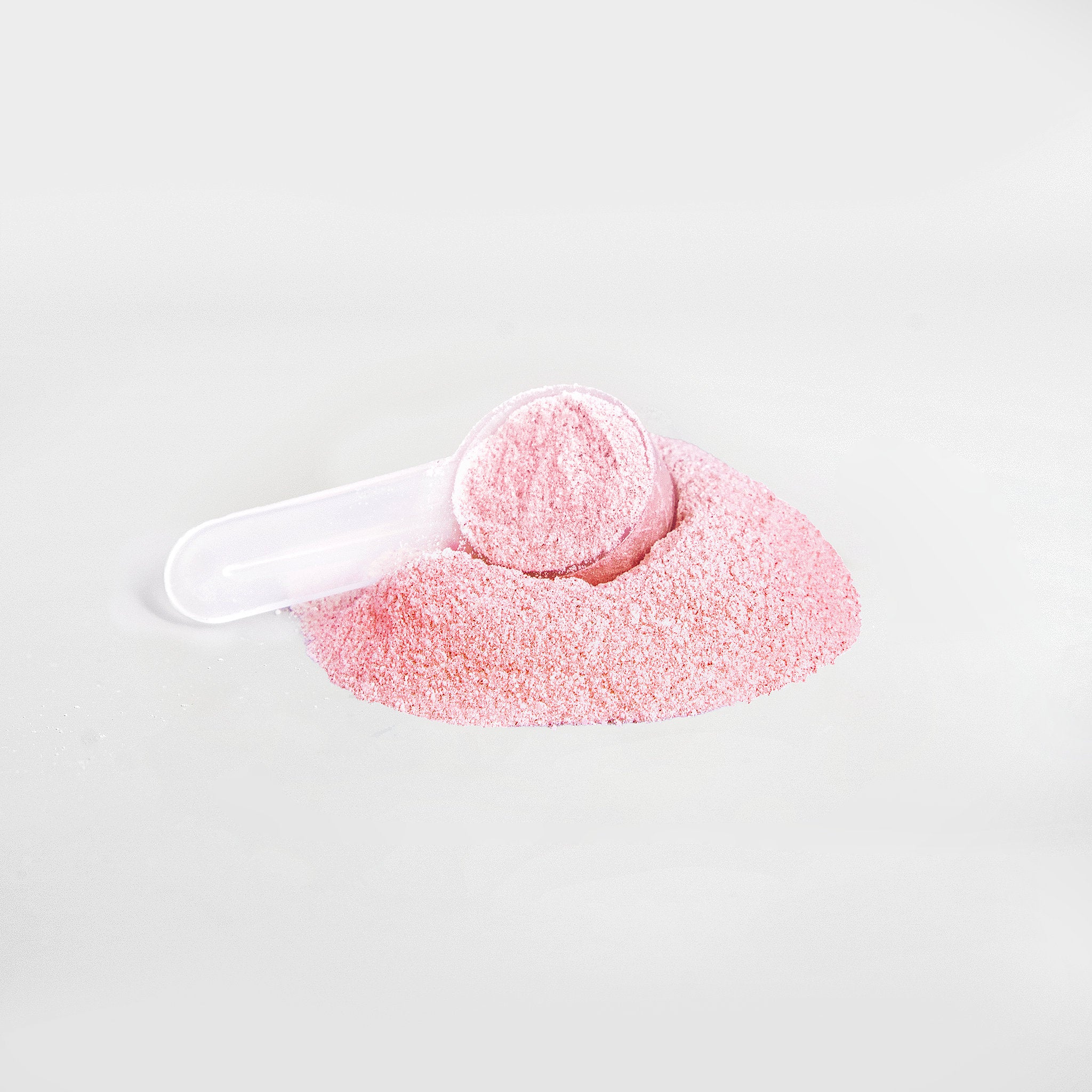 Pink bath bomb with a white scoop on a light gray background