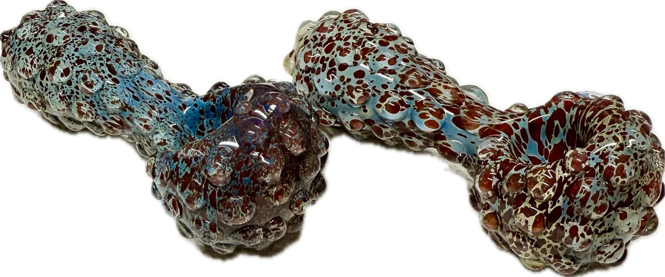 Two Ripkitty 5" blue spike spoon pipes side by side — teal-blue and dark red frit with raised bubble spike texture, front-facing view showing bowl ends and full nodule-covered bodies, white background