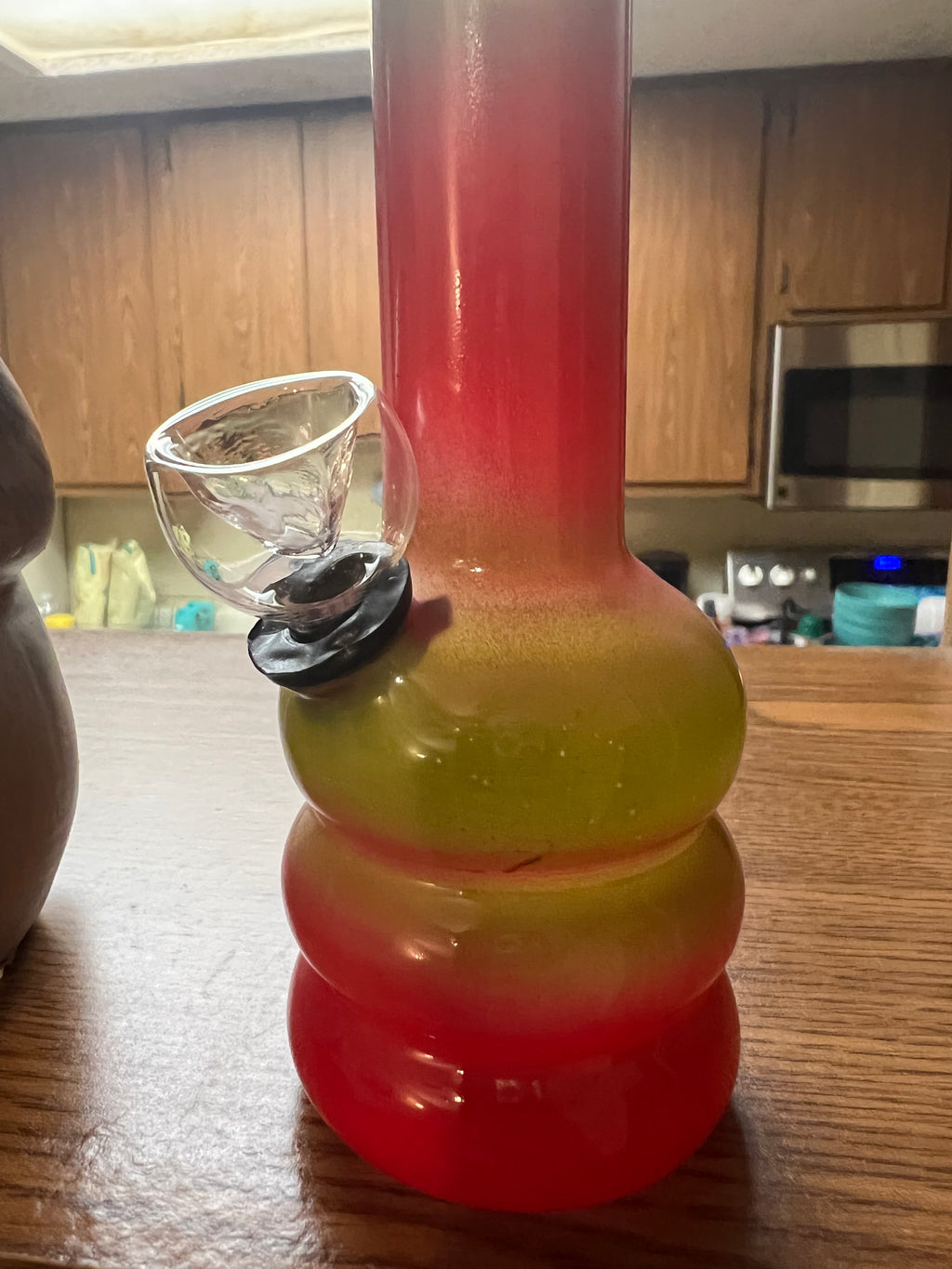 Ripkitty 5-inch soft glass water pipe, red to olive yellow gradient, triple-bubble base, clear bowl piece inserted, kitchen counter with decorative bird figurine